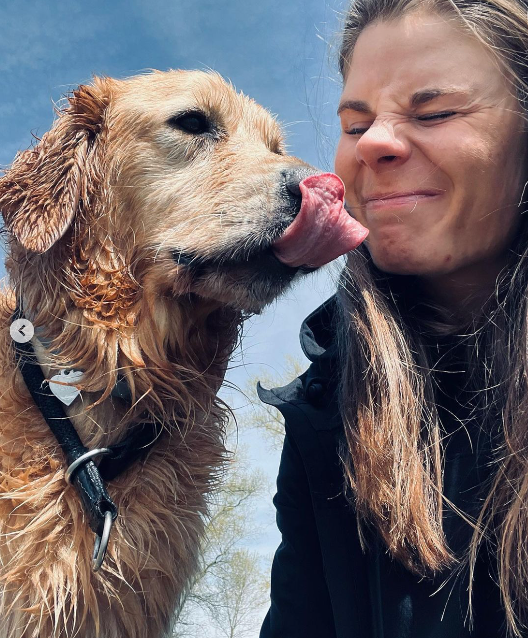 A woman grimaces as a dog licks her face 